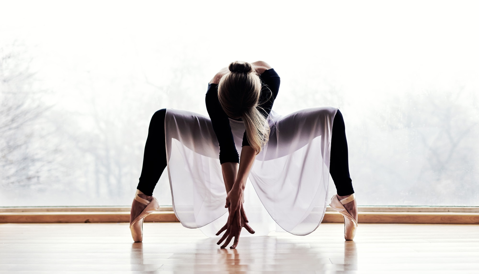 A ballerina crouching low on pointe.